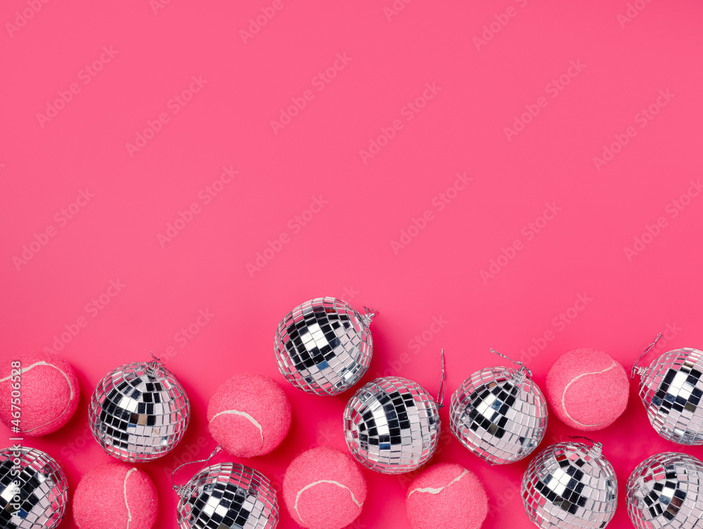 Creative Christmas composition with pink tennis balls and shiny disco balls  on vivid pink background. Minimal Xmas or New Year celebration concept.  Elegant winter holidays banner with copy space. Stock Photo