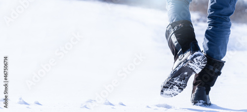 A man walking on a snowy road. Boots close-up. 