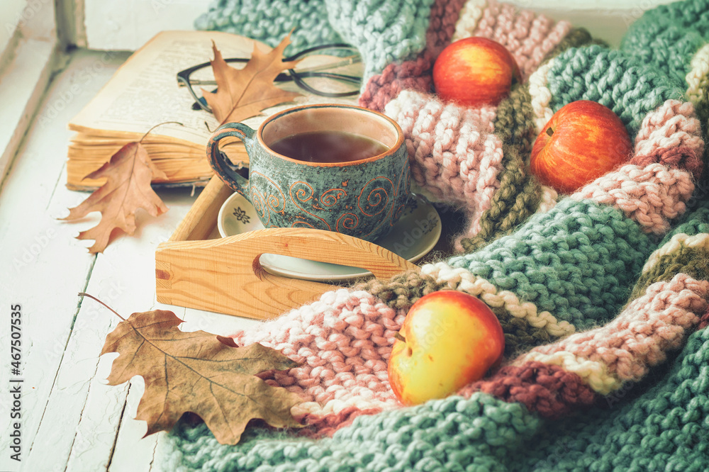 A сup of tea, a book, dry leaves and apples on the wooden windowsill. Autumn concept. A сup of tea, a book, dry leaves and apples on the wooden windowsill. Autumn concept.