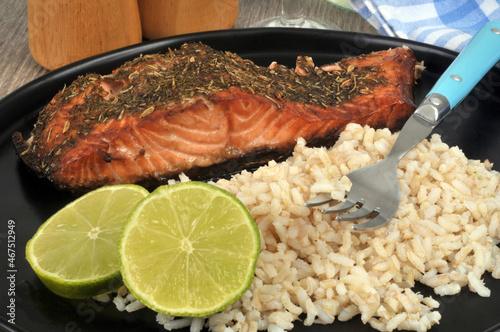 Saumon mariné avec du riz et des rondelles de citron vert servis dans une assiette avec une fourchette en gros plan photo