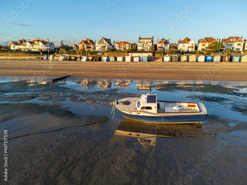 Boat in sea near Southend beach at low tide near Thorpe bay during sunset at a sunny autumn day. reflection on the boat and beach huts. Drone aerial view photo