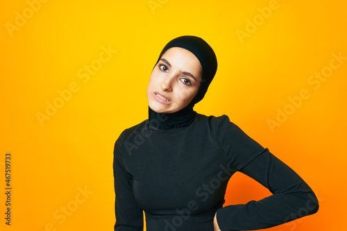pretty woman in black hijab posing fashion hand gesture yellow background © VICHIZH