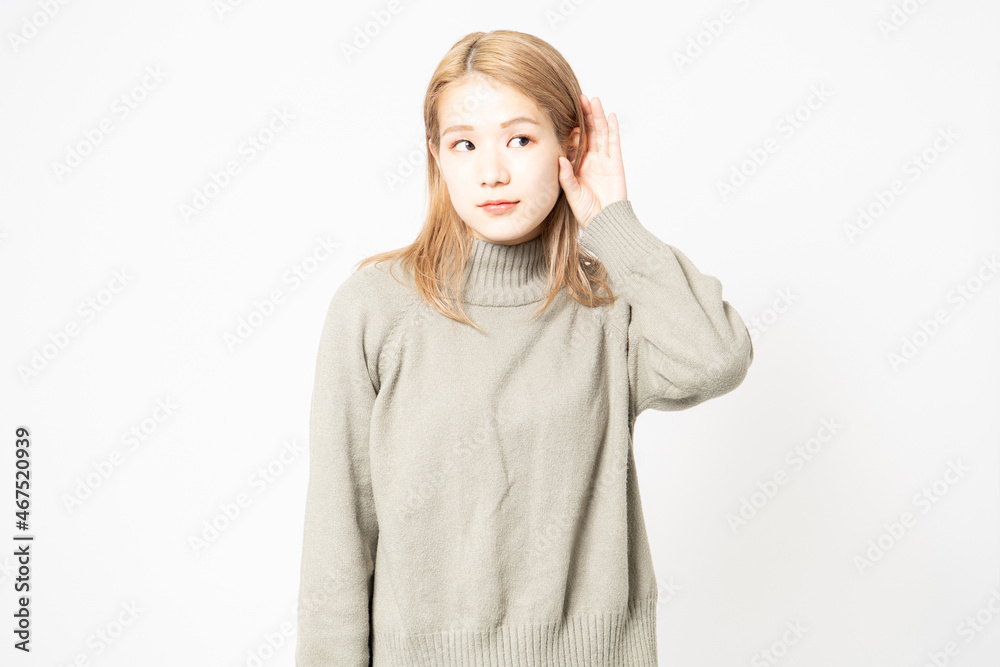 聞き耳を立てて噂を聞くセーターを着た若い女性