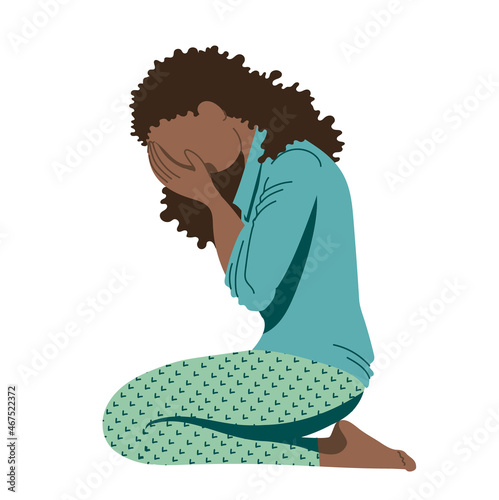Young African-American girl, a teenager suffering from psychological illnesses, depression, anxiety , is sitting on the floor, covering her face with her hands and lowering her head