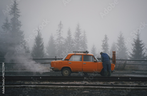 Chelokea repairs an old Soviet car. Frosty morning in the mountains. Ukrainian Carpathian mountains.