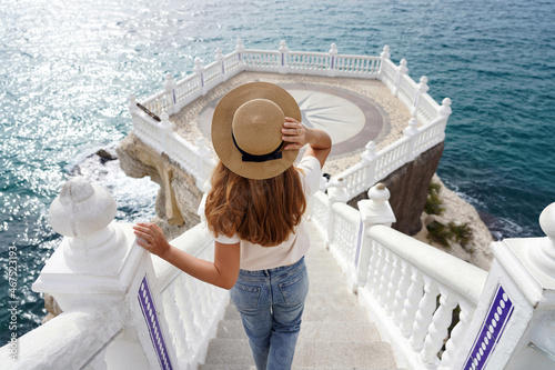 Holiday in Spain. Back view of young traveler woman descends stairs towards the Mediterranean Balcony in Benidorm, Alicante, Spain.