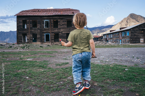Child playing in an abandoned village with wooden houses in beautiful Altai mountains