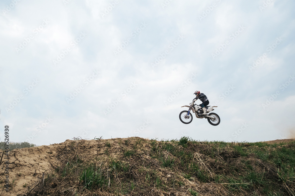 Obraz premium Motorcyclist jumping and riding on rear wheel at enduro motocross training ground