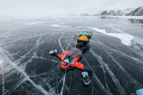 Female tourist Lying on the frozen ice of Lake Baikal. Winter trekking