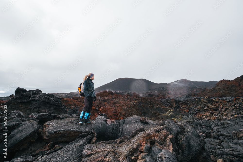 Traveler female walking on the frozen lava of volcano. Hiking in the mountains of Kamchatka