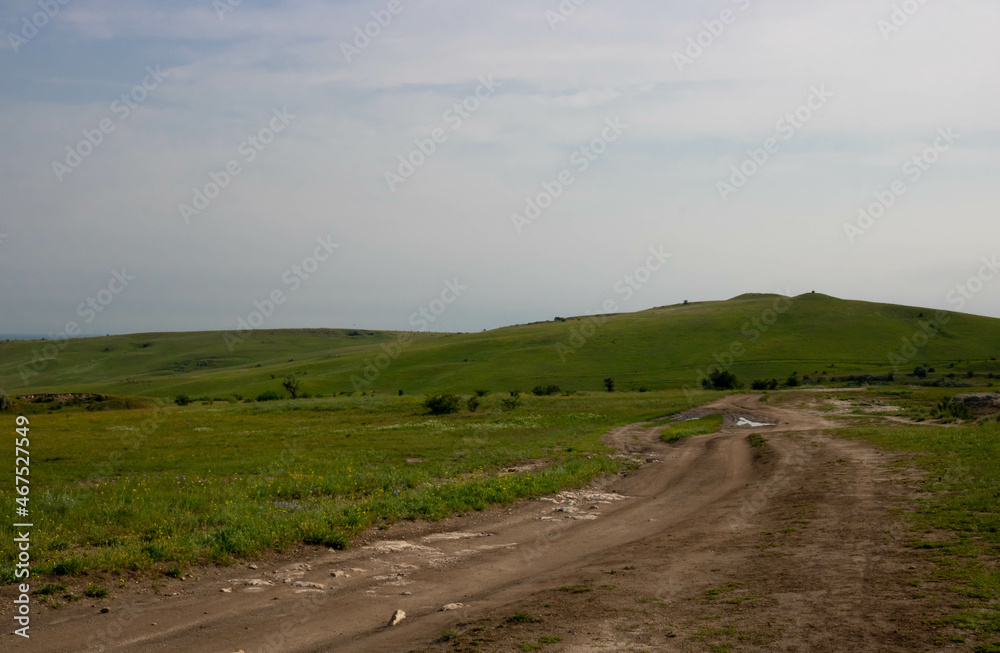 Summer landscape of beautiful green hills and dirt road