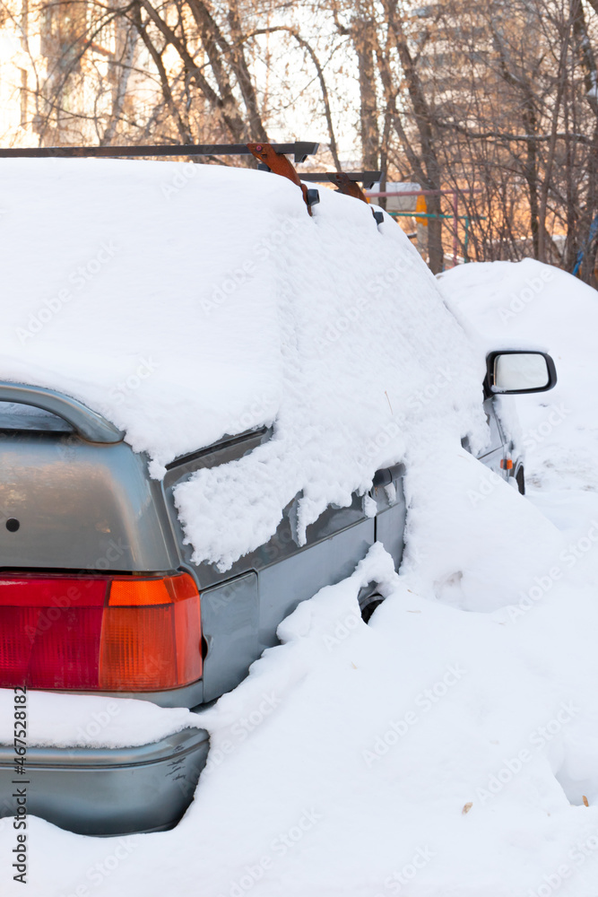 old abandoned broken car parked by the road under a large layer of snow on a cold winter day old abandoned broken car parked by the road under a large layer of snow on a cold winter day