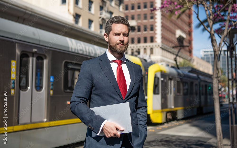 businessman hold laptop for blogging on metro station, freelancer