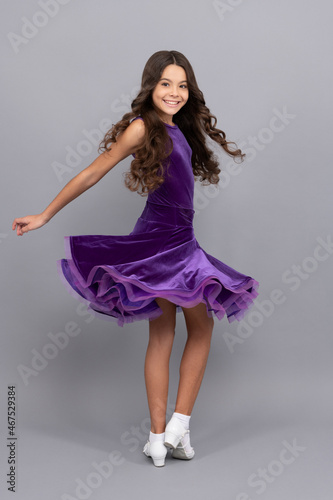 cheerful kid with long curly hair dancing in ballroom dress full length, quickstep