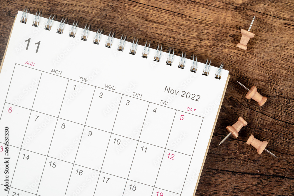 Top view Calendar desk 2022 on November month, The concept of planning and deadline with push pin on wooden table background. Top view Calendar desk 2022 on November month, The concept of planning and deadline with push pin on wooden table background.