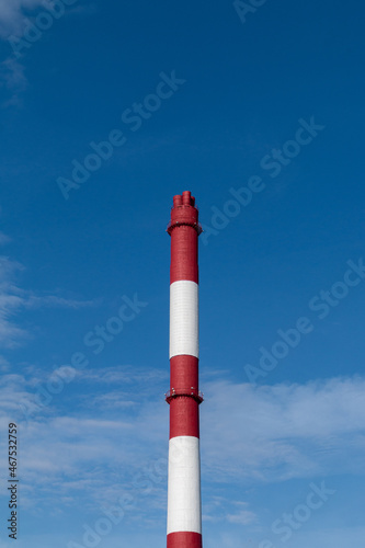 red and white chimney against blue sky. environment pollution concept