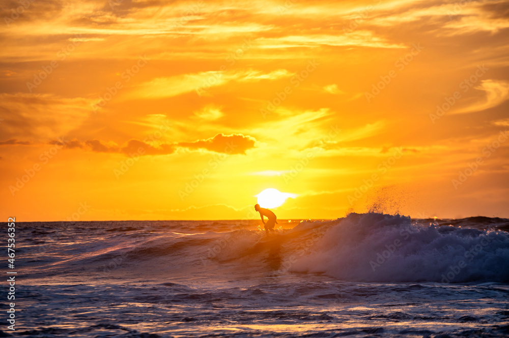 Silhouette eines Surfers beim Wellenreiten auf einer Welle mit wunderschönen Sonnenuntergang