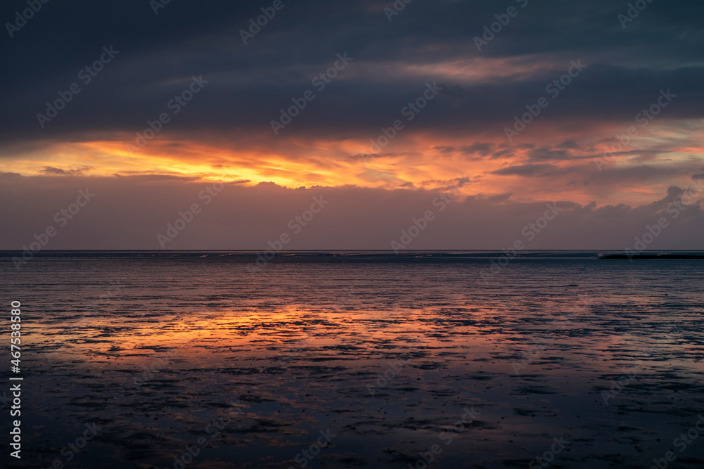 The Wadden Sea in Buesum during sunset, reflecting in the wet sand, Germany.
