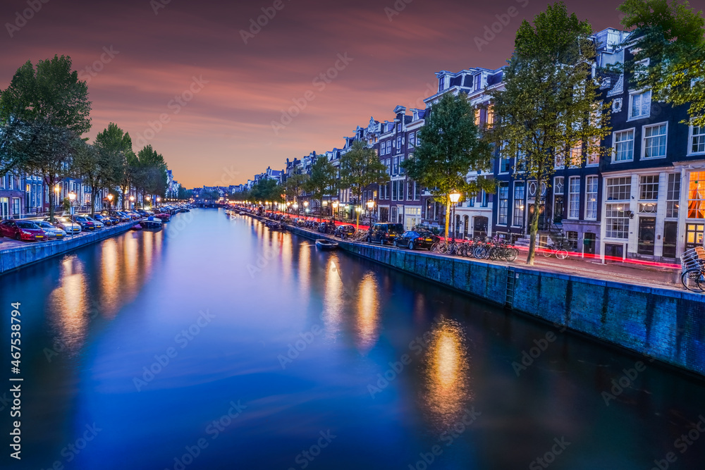 Beautiful Dutch buildings on both sides of the canal at night in Amsterdam Netherlands.