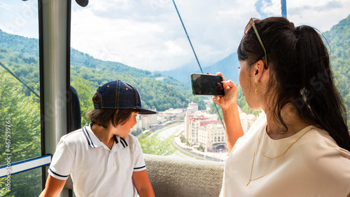Mother and son in ski lift cabin in summer. Passengers on a cable car