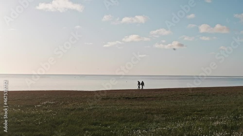 People walk on shore near Kara sea talking. Sunny summer afternoon on Yamal peninsula. Calmness and tranquility. photo