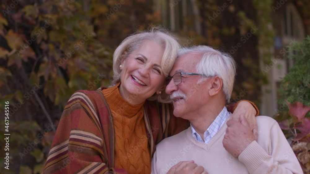Handsome senior couple embracing in front of the old house Handsome senior couple embracing in front of the old house