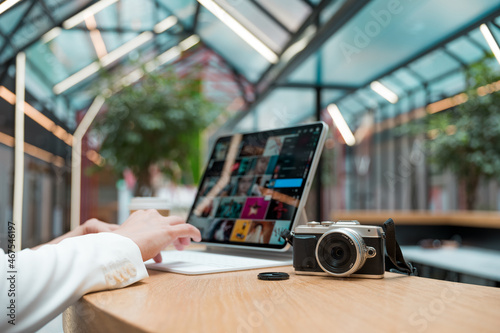 A freelance photographer works remotely, a thin mobile computer with a photo on the screen and a camera in the foreground. Creative work, retouching or creating designs.