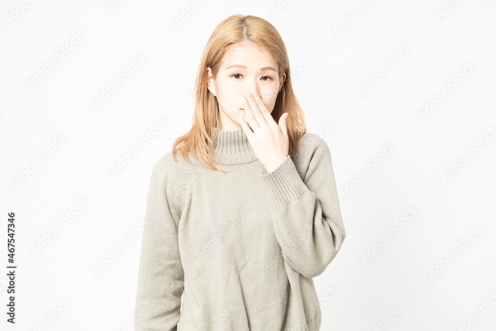 内緒のポーズをするセーターを着た若い女性