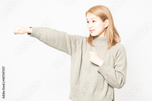 パンチのジェスチャーをするセーターを着た若い女性