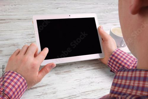 The man works on the tablet at the table.