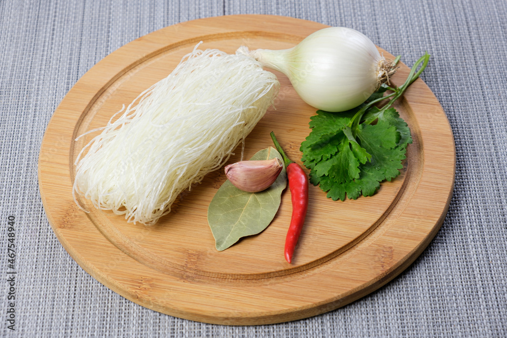 Dry funchose and ingredients for preparing an Asian dish. Spices and assorted vegetables are ready to cook with Chinese glass noodles. Cooking vegetarian meals. Dry funchose and ingredients for preparing an Asian dish. Spices and assorted vegetables are ready to cook with Chinese glass noodles. Cooking vegetarian meals.