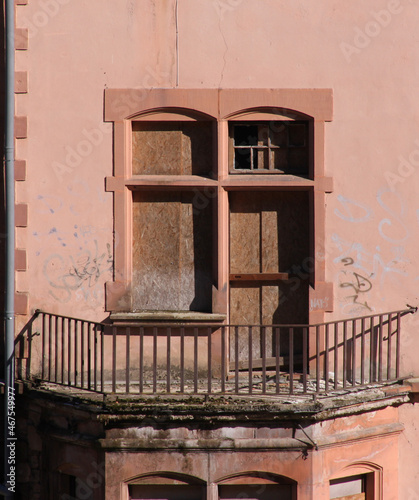 Balcony with railing, nailed window and shut door at the facade of an abandoned historical villa in the town of Trier Ehrang in Germany photo