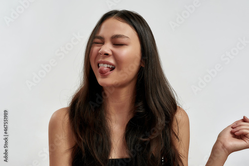Millennial asian woman show tongue feeling discontent