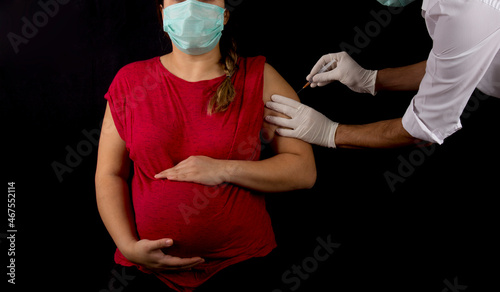 pregnant woman getting covid-19 vaccine on black background