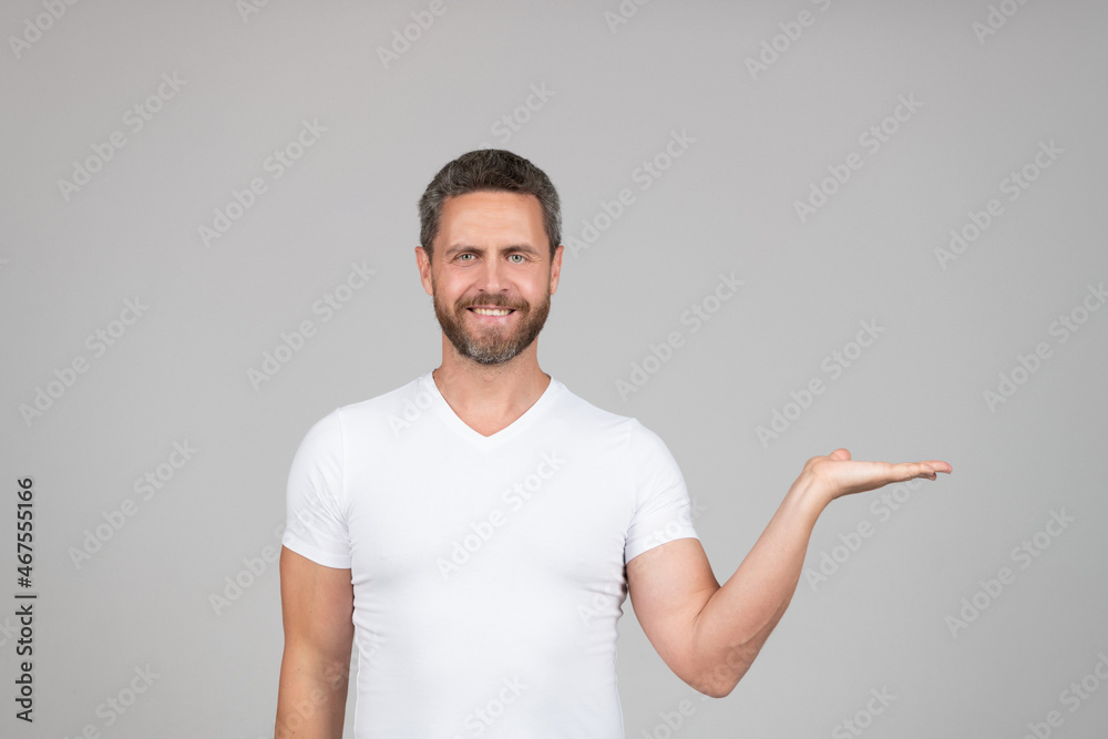 Happy caucasian guy show open hand grey background copy space, presenting product.