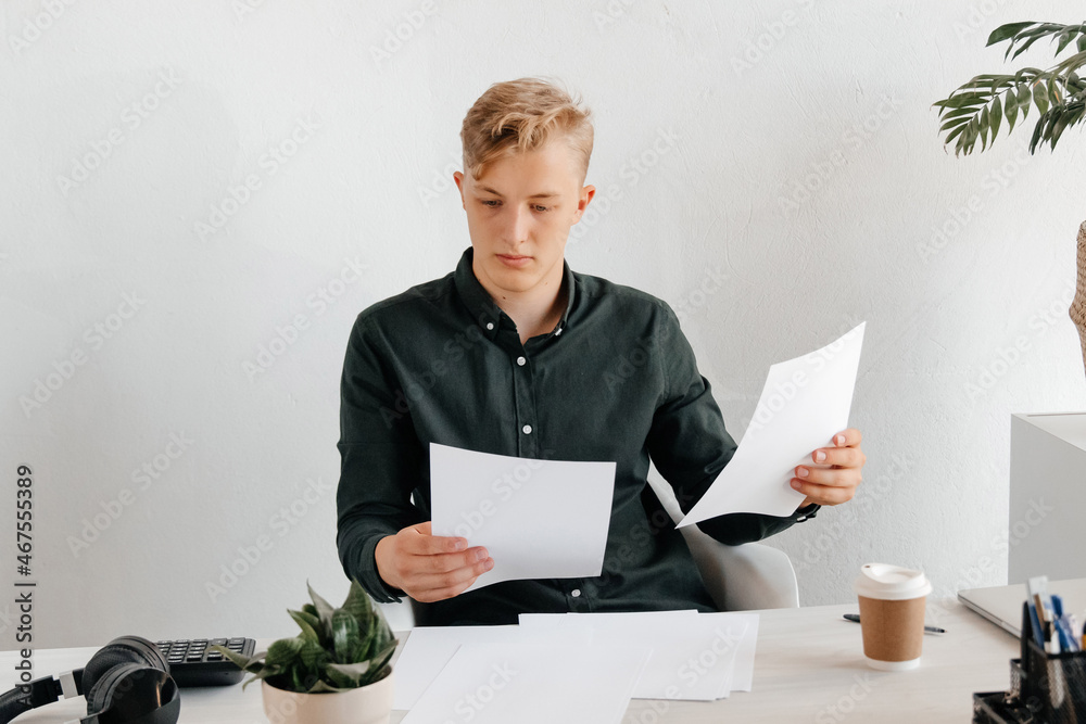 Confused young businessman comparing the documents, productive day at the office Confused young businessman comparing the documents, productive day at the office