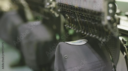 Sewing machine stitching onto hat garment on industrial machines