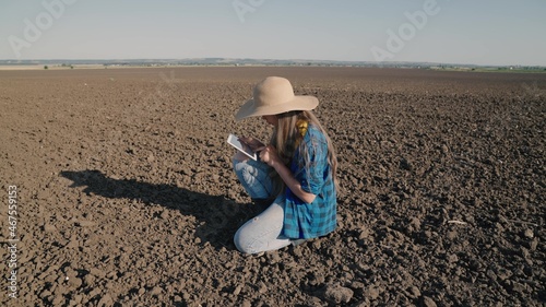 a farmer with a tablet works on the land, agriculture in the spring, an agronomist checks the soil in the field, a plot of a plantation for planting seedlings sprouts in the ground, a rural farmland