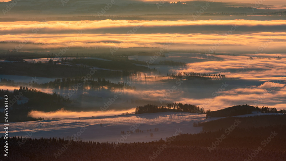 Foggy valley with cloud rolling over the hills at sunrise in winter.