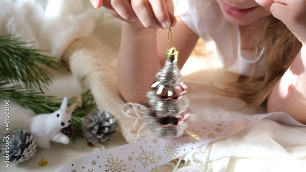 Child girl preparing  winter holidays and Christmas at home. She laying on floor and playing with Christmas toys.