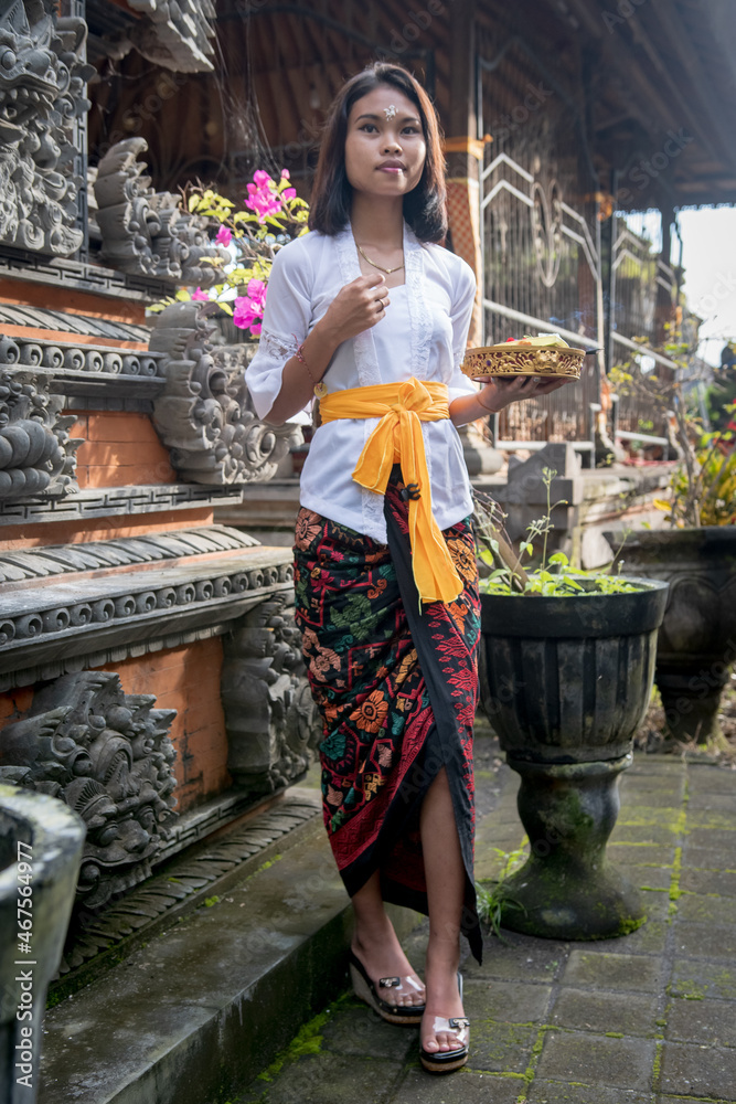 Young local Girl in a Balinese temple carrying offerings, Bali, Indonesia.