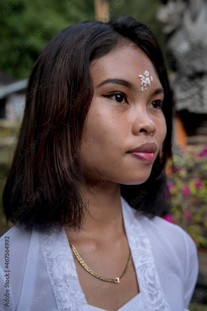 Portrait of a girl in a Balinese temple carrying offerings, Bali, Indonesia.