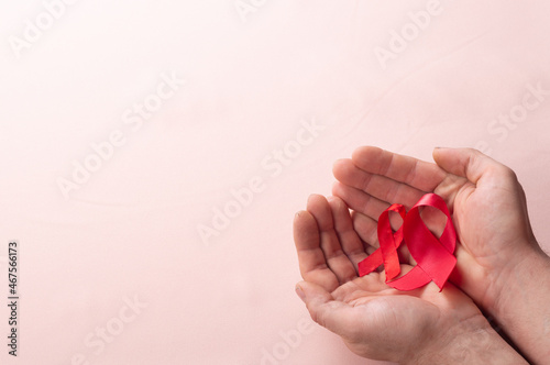 healthcare and medicine concept two hands holding red ribbons HIV and AIDS awareness on brown background close up