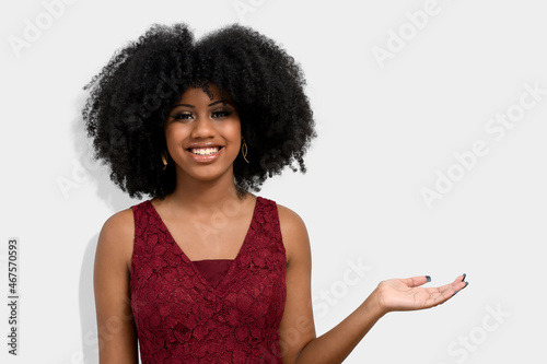 portrait of a dark-skinned girl with afro haircut, points with her front fingers, shows blank space for her promotion, isolated on gray background People, advertising concept