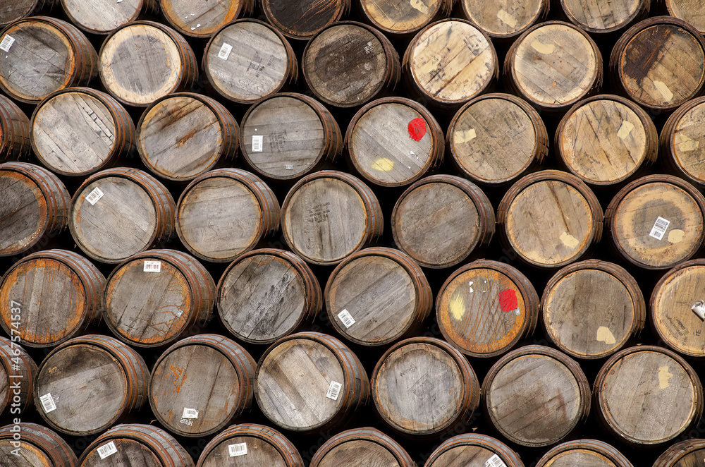 Stacked oak barrels of the kind used for storing whiskey or wine. 