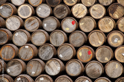 Stacked oak barrels of the kind used for storing whiskey or wine. 