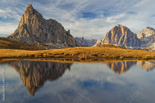 Mountains reflecting on a small mountain lake waters in Passo Giau