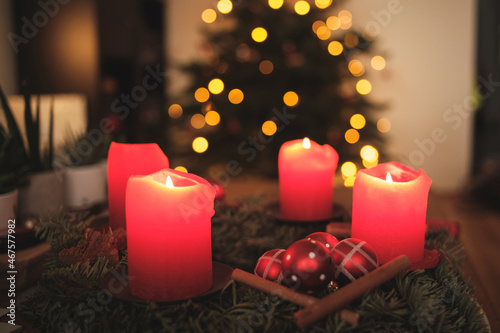 Adventskranz mit Kerzen und Weihnachtsbaum im Hintergrund