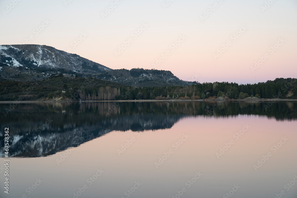 Alpine landscape at nightfall. Magical view of the Andes mountains, forest and lake at sunset. Beautiful symmetrical reflection in the water.