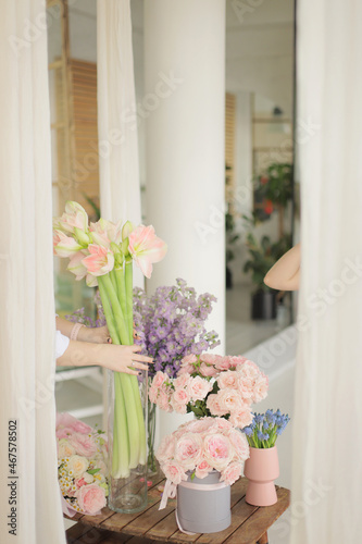 Different flowers in glass vase on wooden table. Pink roses  purple delphinium and peach amaryllis.